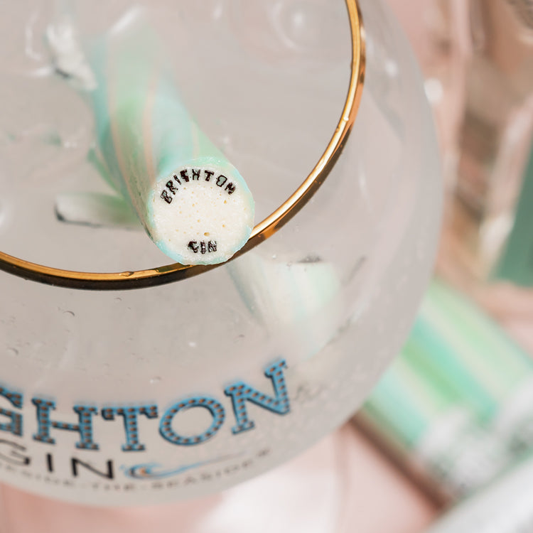 Gold rimmed copa gin glass with Brighton Gin logo and stick of minty rock